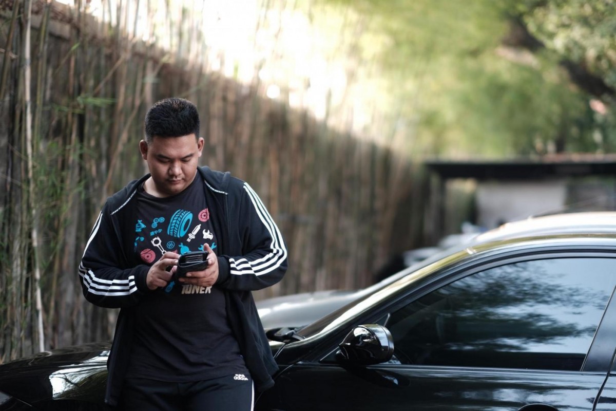  Evan Pratama sedang menggunakan handphone dengan baju serba hitam