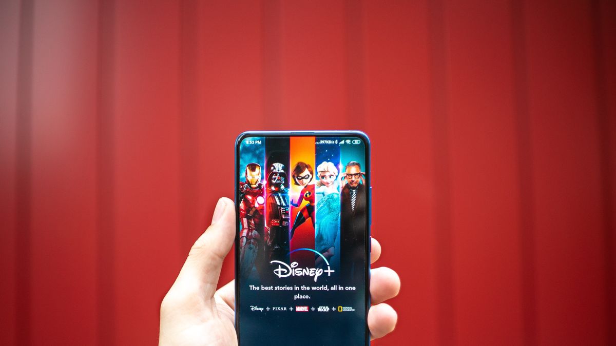 Tampilan menu Disney+ dalam sebuah layar smartphone di depan background warna merah