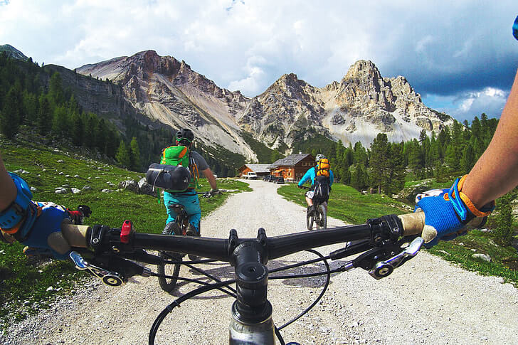 Tampak sepasang tangan memegang handlebar sepeda ketika bersepeda di area pegunungan