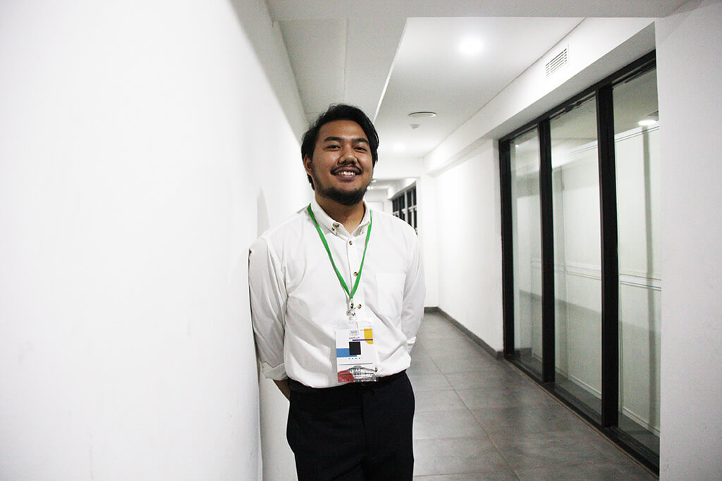 Ario bersandar di tembok menggunakan kemeja putih dan trouser hitam