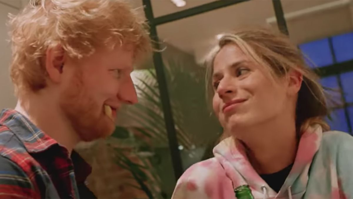 Ed Sheeran mengenakan kemeja kotak-kotak, menghibur sang istri yang mengenakan sweater warna-warni.
