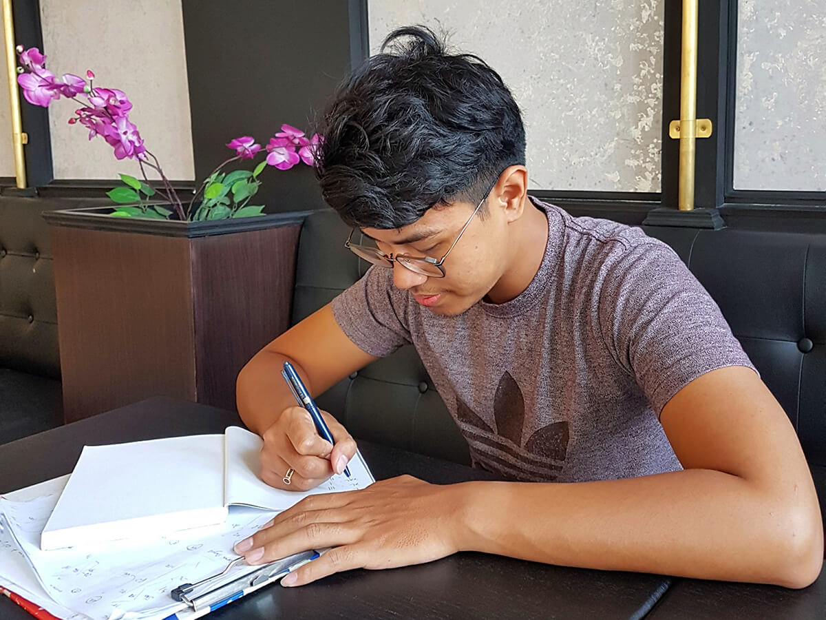 Rony sedang membuat sketsa pakaian batik hasil karyanya