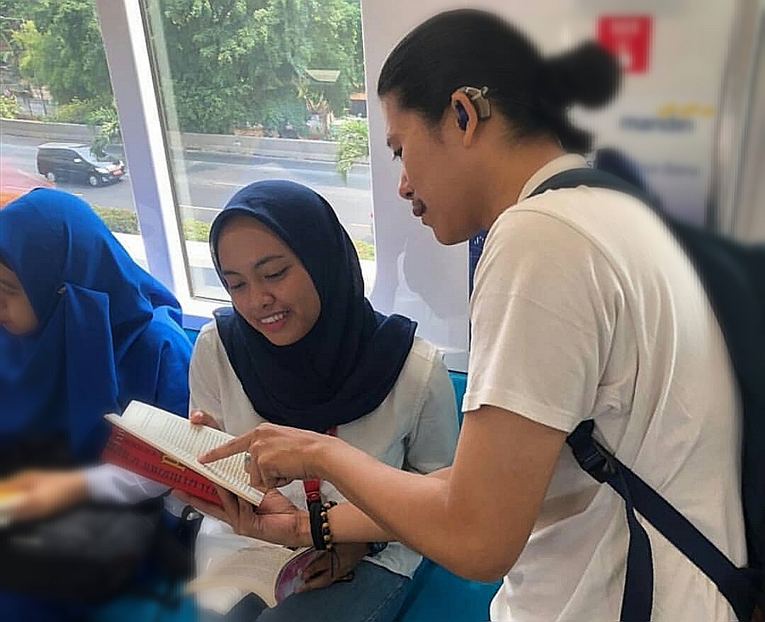 Salah satu Teman tuli sedang menunjukkan buku yang ia baca ke relawan non-disabilitas